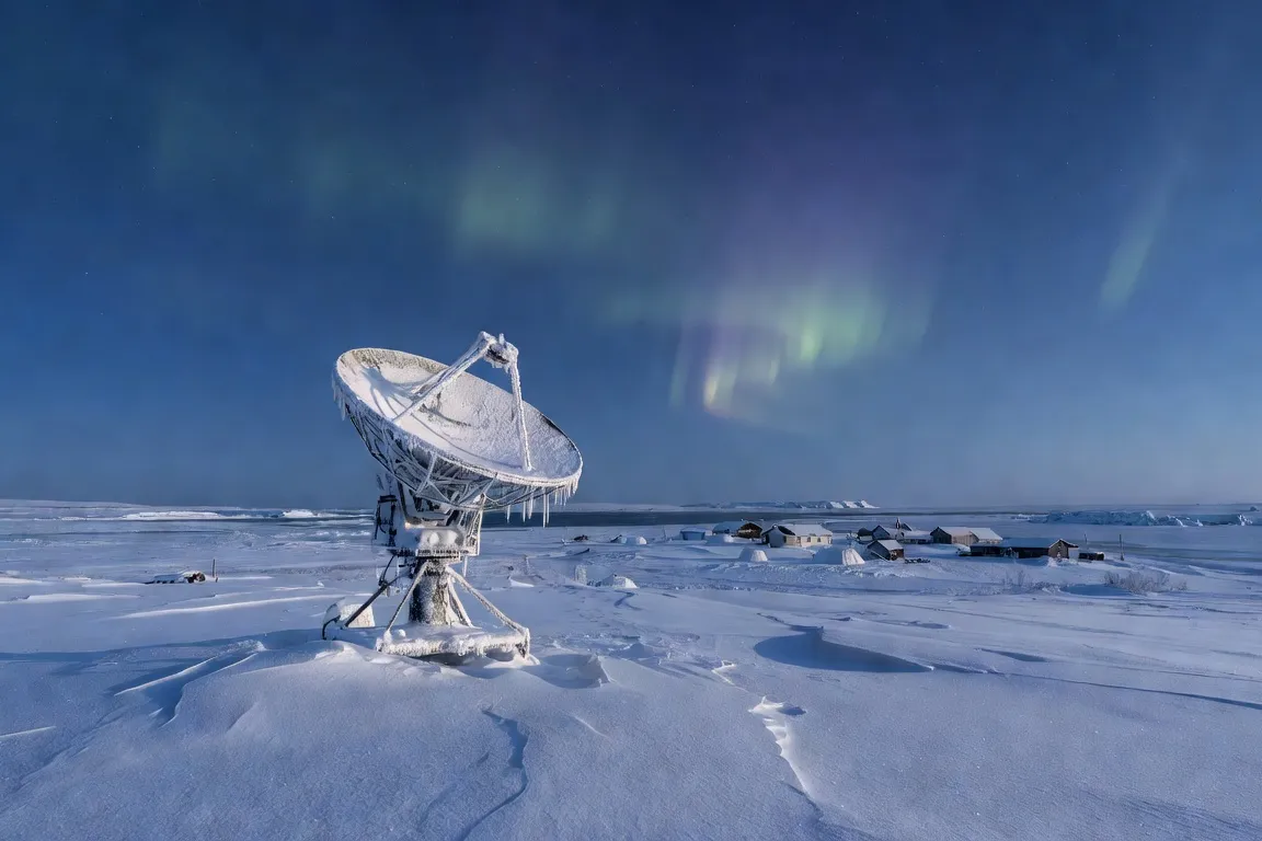 Antenne satellite parabolique dans la toundra enneigée du Nunavik avec village côtier arctique en arrière-plan